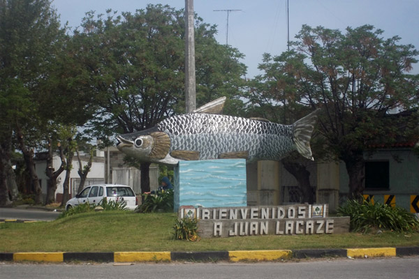 Monumento de un sábalo ubicado en una plaza sobre un cartel que dice "ienvenido a Juan Lacaze"