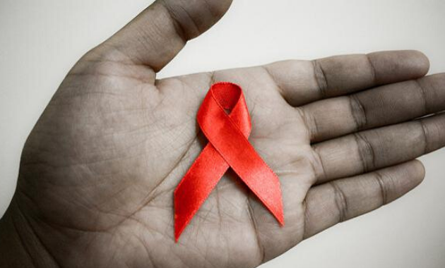 Fotografía de una mano sosteniendo un lazo rojo, el símbolo internacional de la lucha contra el Sida.