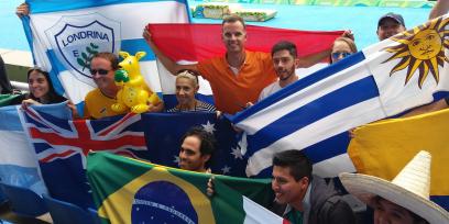 Grupo de personas de diferentes países con sus banderas en tribuna de estadio olímpico.