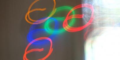 Imagen de círculos de colores realizados con un haz de luz, sobre un fondo claro.