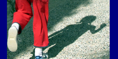 Imagen de unas piernas infantiles y su sombra reflejada en un patio exterior.