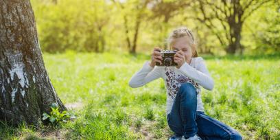 niña tomando fotografía en un parque