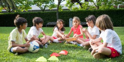 grupo de niños sentados de forma circular sobre el césped