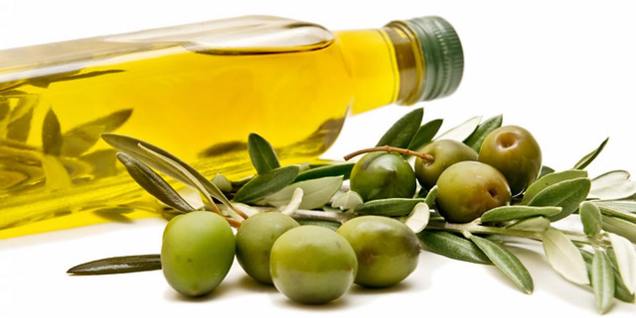 Botella con aceite de oliva y una rama con aceitunas a su lado
