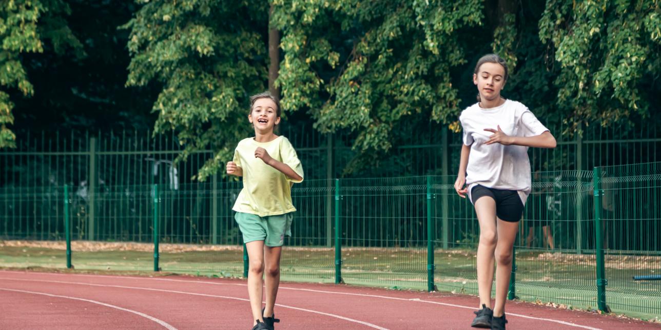 Dos niñas corriendo en pista de atletismo