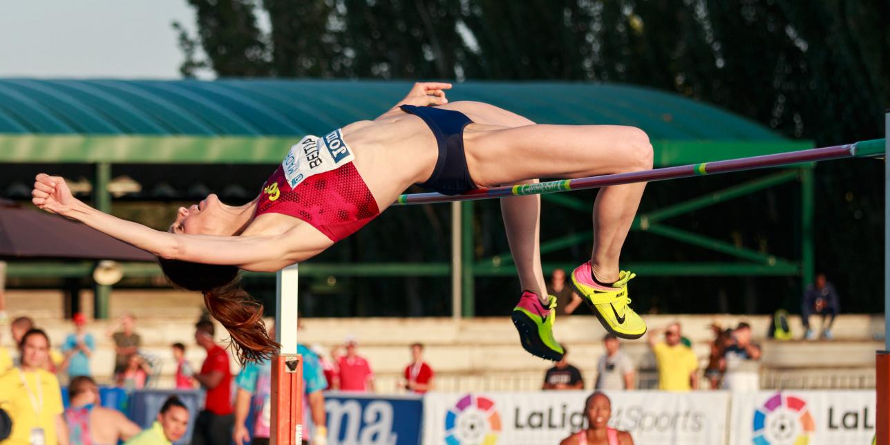 Imagen de una atleta en fase de vuelo del salto sobre un obstáculo.