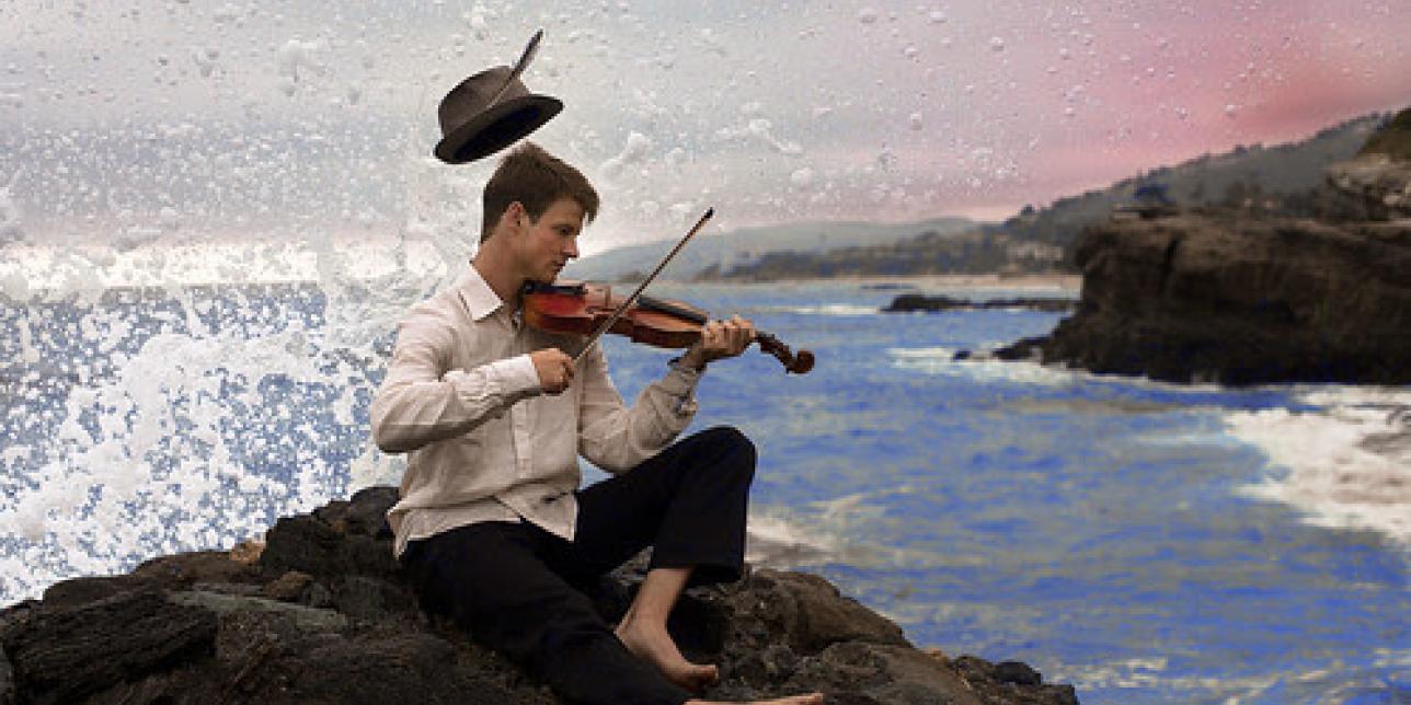 Hombre tocando el violín junto al mar