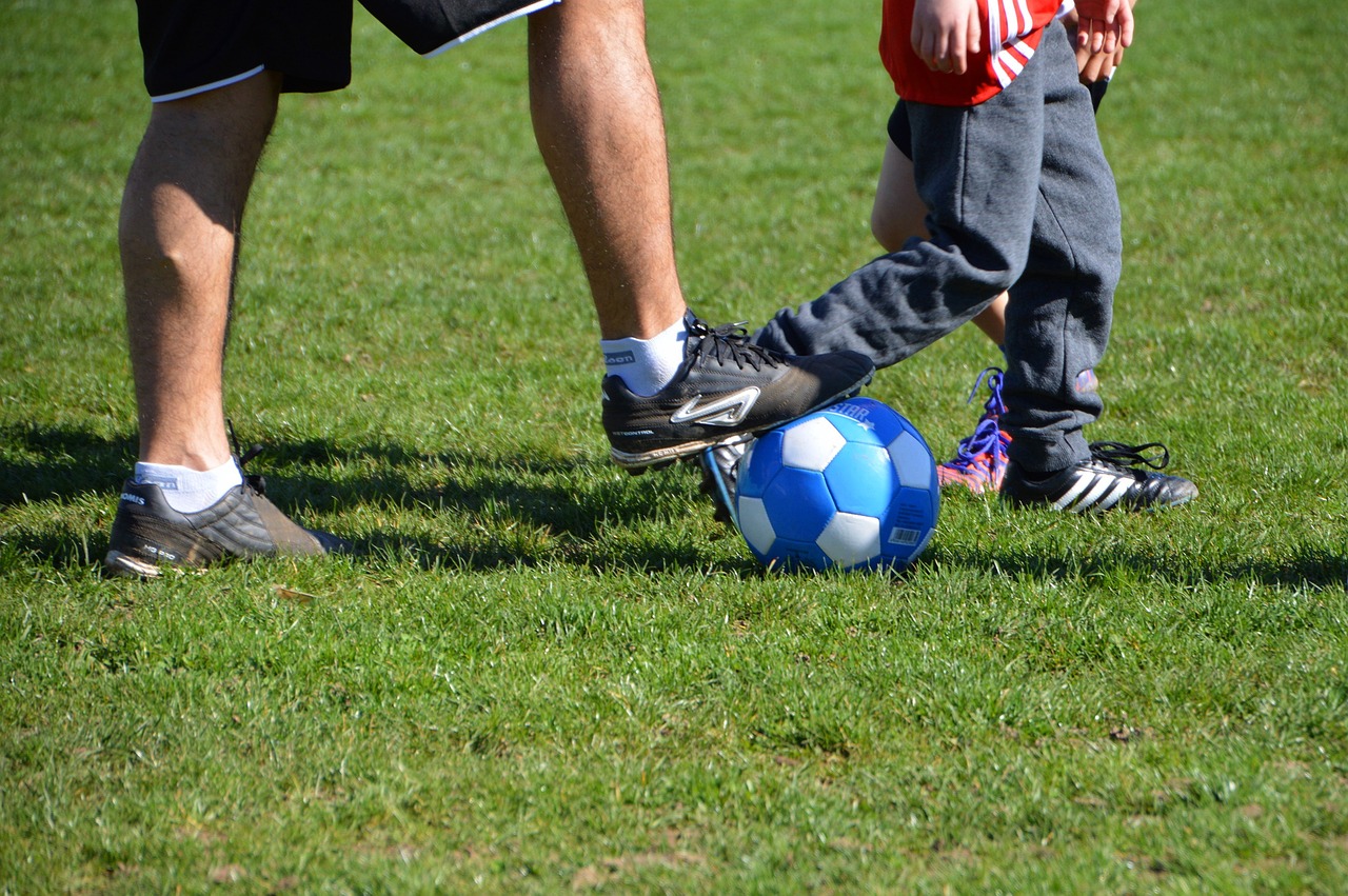 Adulto y niño con pelota de fútbolen los pies