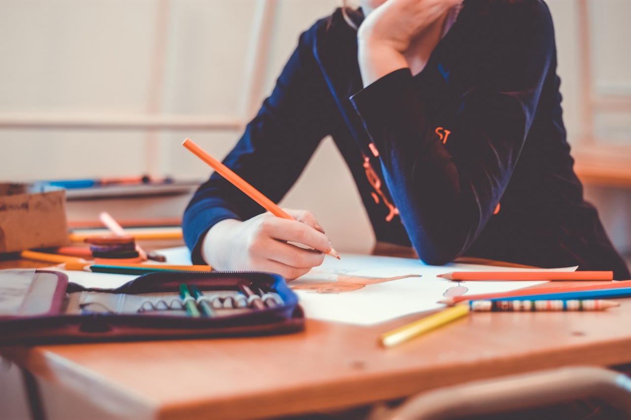 adolescente haciendo deberes en un cuaderno sobre un escritorio