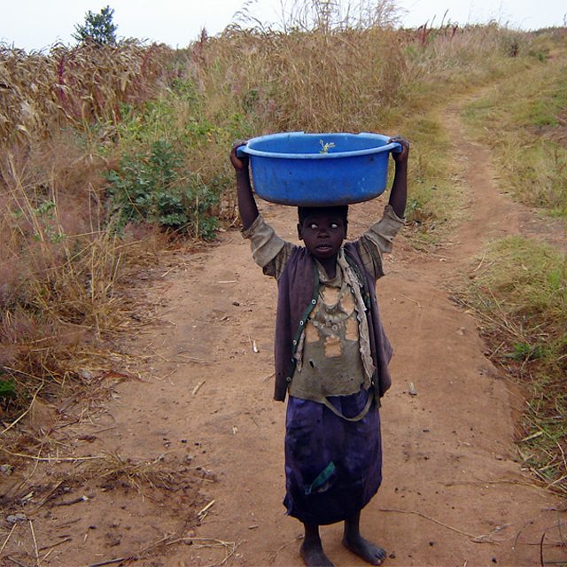 Niño que sostiene sobre su cabeza un recipiente con el que busca agua