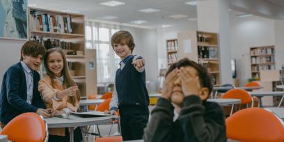 Niños riéndose se forma burlona y señalando a otro niño
