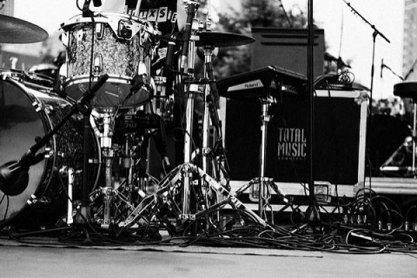 Fotografía en blanco y negro de equipos e instrumentos al costado de un gran escenario.