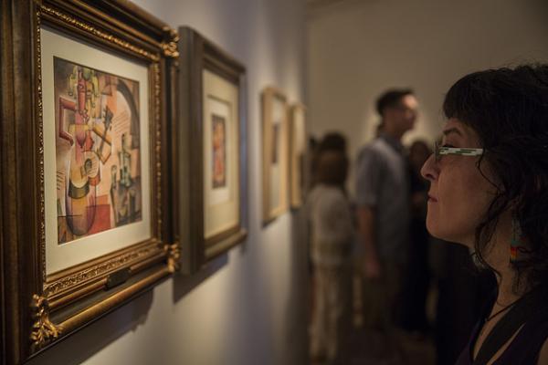 Una mujer observando una pintura de Xul Solar