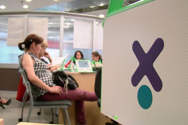 Imagen de una XO con docentes de fondo, participando de un taller.