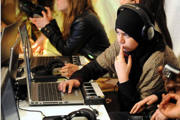 Niña trabajando con una computadora portátil y un teclado musical.