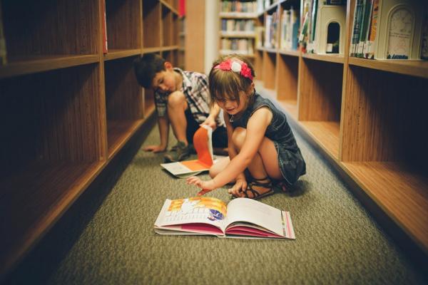 Niños leyendo libros cerca de biblioteca