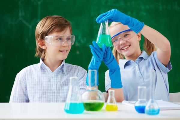 Dos niños sujetando un matraz con líquido verde