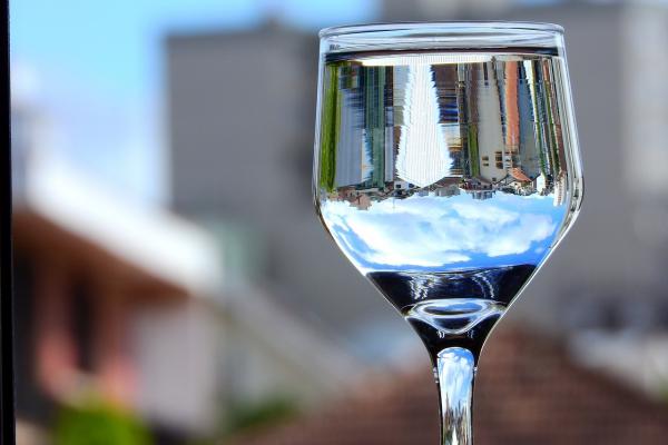 Copa con agua. A través de ella se ve la imagen invertida de unos edificios lejanos.