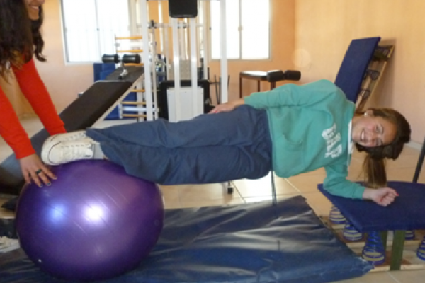 Jóvenes realizando trabajo sobre la región del CORE con pelota de fitball.