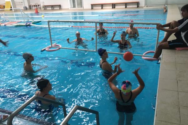 Jóvenes jugando a juego con pelota y red en la piscina.