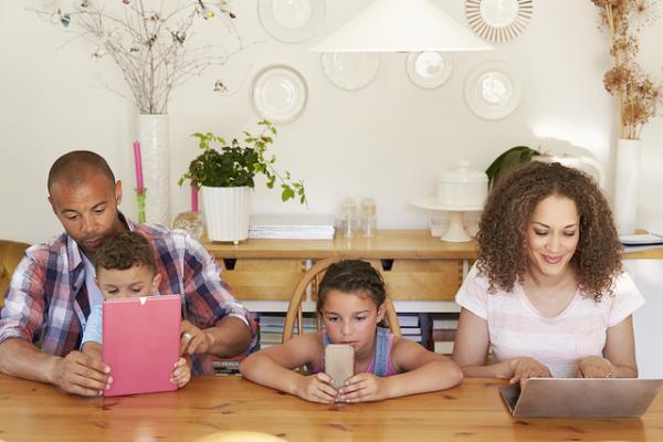 Familia utilizando diversos dispositivos como celular, tablet y notebook