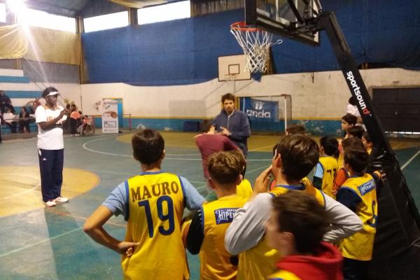 Profesor explicandole a alumnos sobre lanzamiento en Básquetbol.