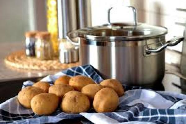 Imagen que muestra una olla, junto a alimentos crudos y de fondo, envases con condimentos