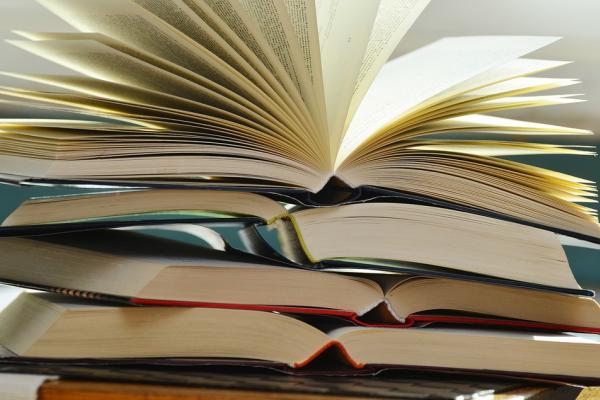 Imagen que muestra libros apilados y uno de ellos abierto