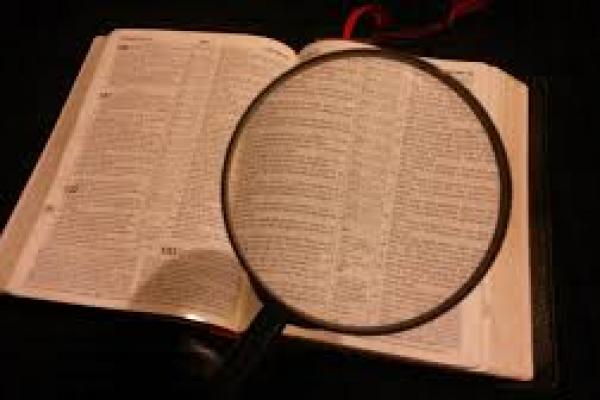 Imagen que muestra un libro abierto, debajo de una lupa, como símbolo del acto de investigar