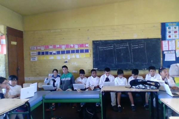 Alumnos de sexto año en clase usando laptops