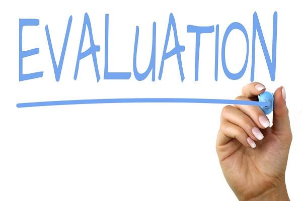 Mano escribiendo en un pizarrón la palabra evaluación en inglés: evaluation.