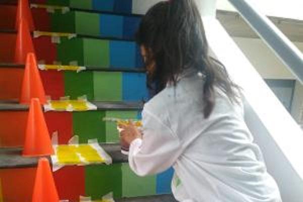 Niña pintando los escalones de una escalera.