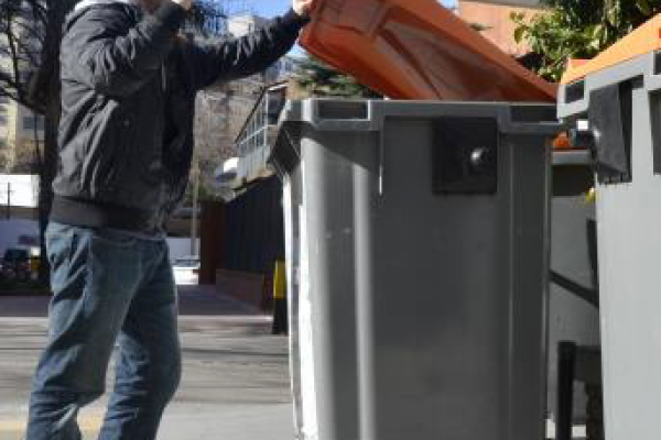 Persona tirando basura en un contenedor.