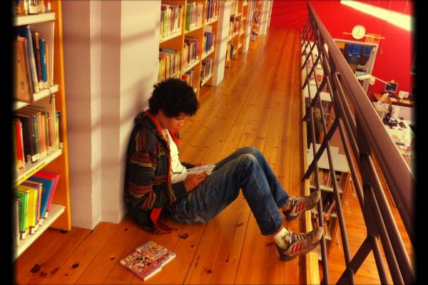 Joven leyendo un libro en una biblioteca.