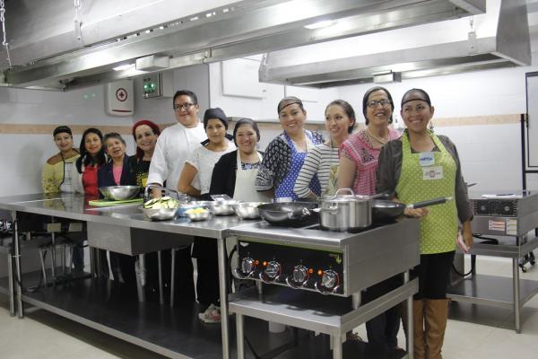 Jovenes atras de una mesada,  en un taller de cocina.