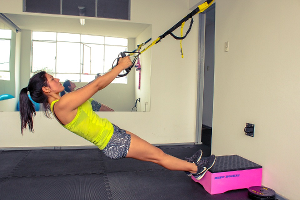 Mujer realizando ejercicio con trx.