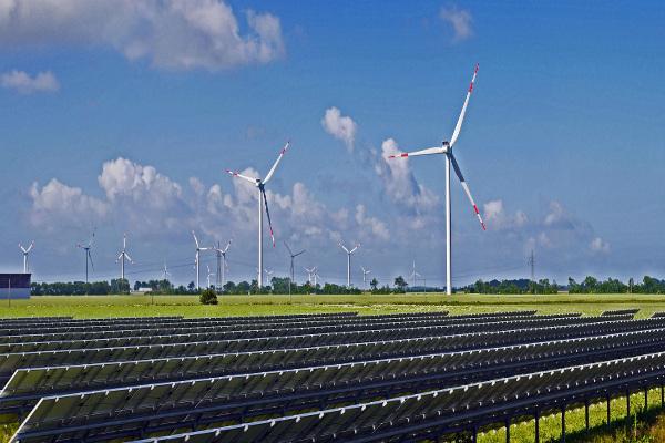 Foto campo con paneles solares y molinos eólicos.