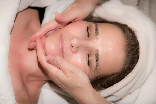 Fotografía de rostro al que le aplican una crema facial