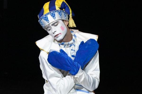 Foto de payaso arlequín con rostro triste, abrazándose, agachado.