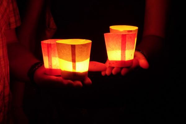 Velas encendidas dentro de vasos de papel sobre las manos. Imagen libre de derechos de autor. 