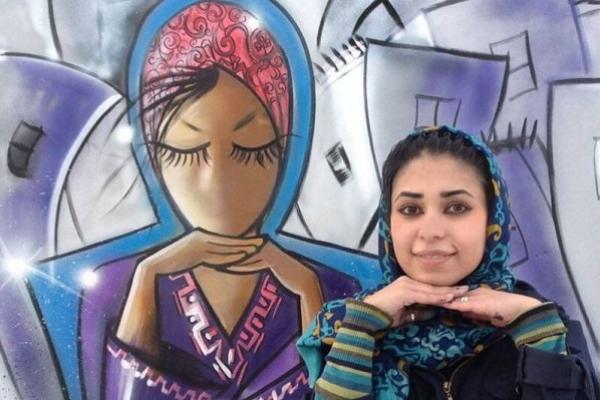 Fotografía de Shamsia Hassani y una de sus graffitis sobre una mujer afgana, la imagen tiene tonalidades lilas y celestes.