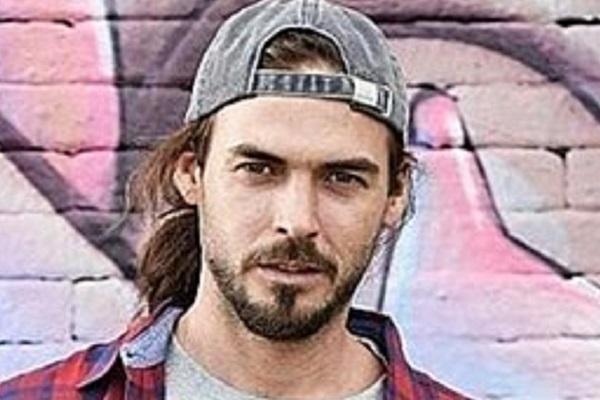 Fotografía de José Gallino en primer plano y en el fondo una pared de ladrillos graffiteada.
