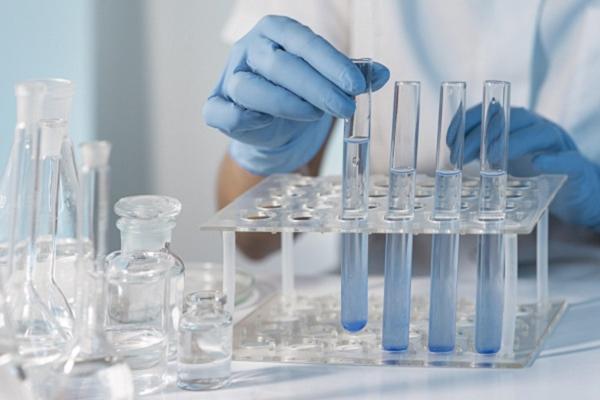 Imagen de una persona trabajando en el laboratorio con una gradilla que contiene tubos de ensayo