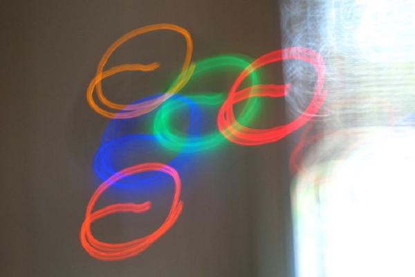 Imagen de círculos de colores realizados con un haz de luz, sobre un fondo claro.