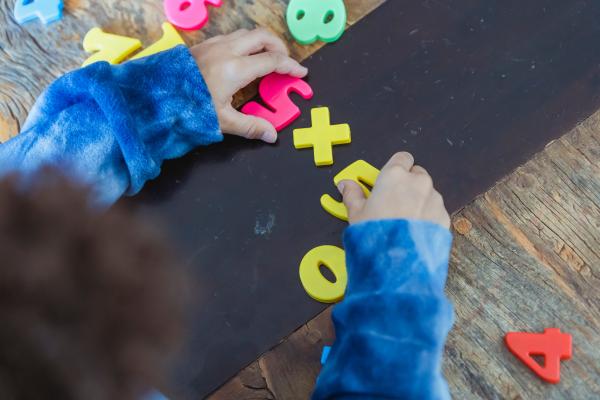 Niño planteando con números de juguete la multiplicación 5x5