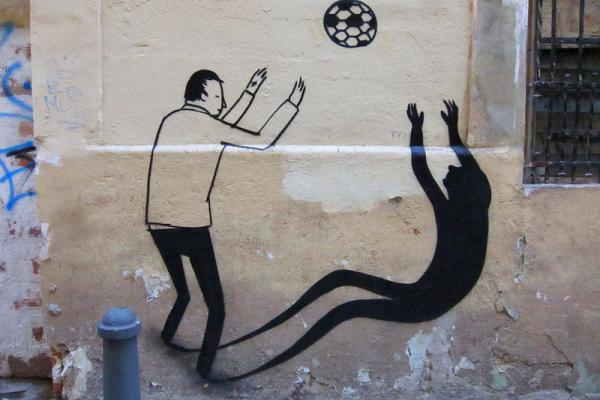Imagen de un graffiti en un muro de un niño jugando con su sombra.
