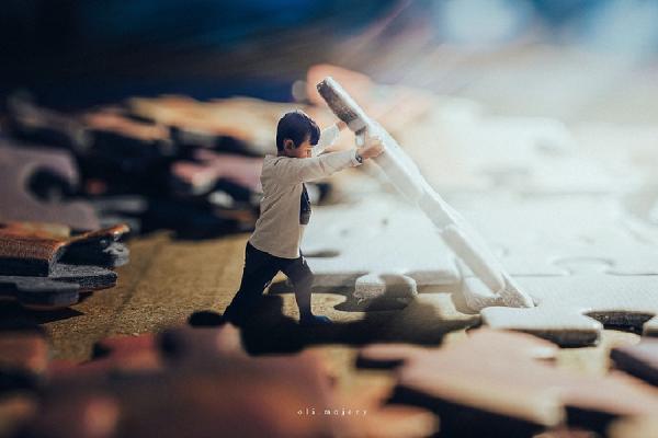 Imagen editada de un niño jugando con piezas de puzzles muy grandes que le sobrepasan en altura.