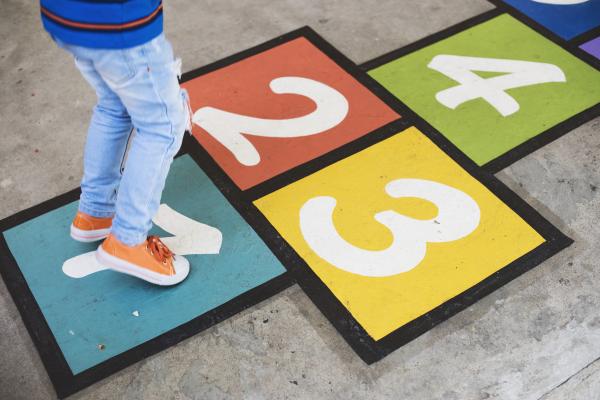 imagen decorativa con niña saltando sobre una rayuela multicolor