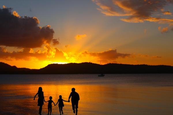 Siluetas de una familia con una puesta de sol en la costa