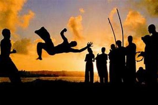 Personas reunida haciendo capoeira al atardecer